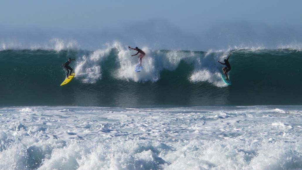 Surfers standing up on the same wave. Photography